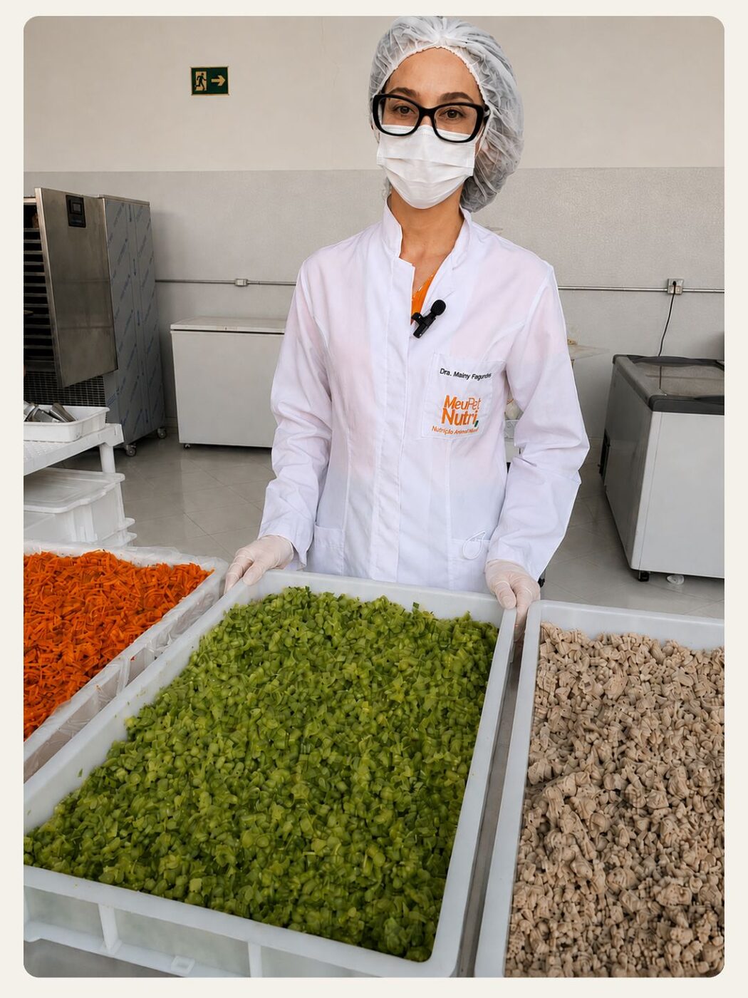 Dra. Mainy, responsável técnica da Meu Pet Nutri, na cozinha de produção com bandejas de vegetais frescos
